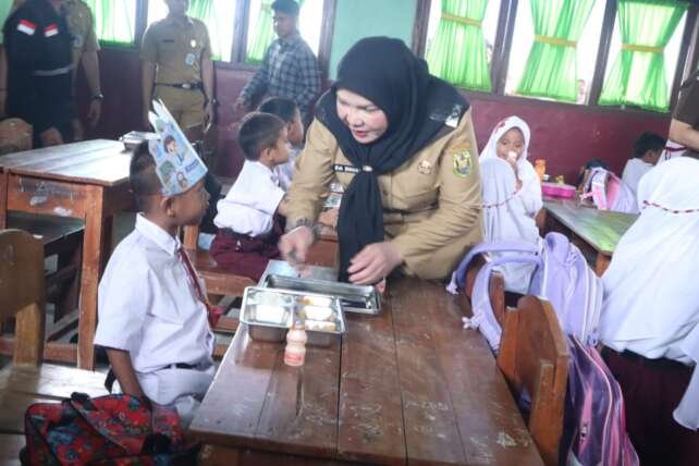 Wali Kota Eva Dwiana bercengkerama dengan seorang murid seputar menu MBG yang disajikan.